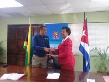 The Minister of Health of Jamaica, Dr. Christopher Tufton, and H.E. Mrs. Inés Fors Fernández, Ambassador of Cuba, shake hands after signing the agreements.